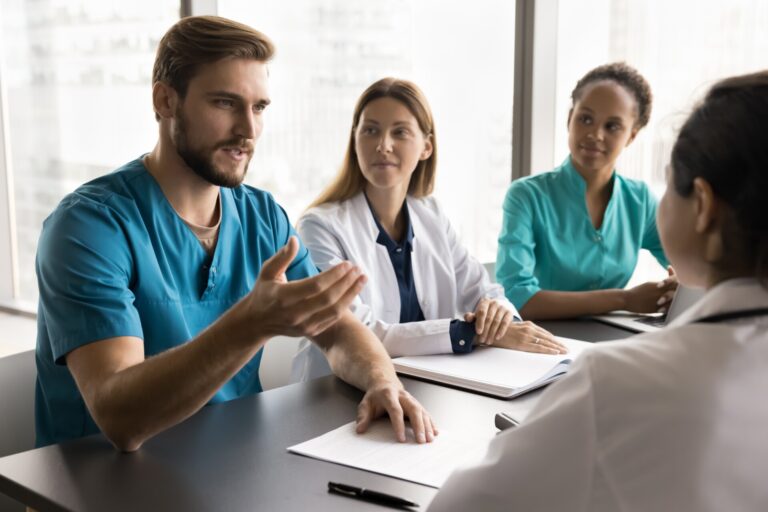 Serious,Young,Doctor,Man,Speaking,To,Diverse,Colleagues,,Discussing,Job,